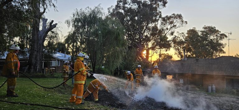 Photo of fire fighters putting out a fire with fire hoses on flat ground