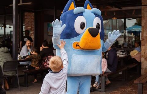 Image of a small child giving Bluey a high five