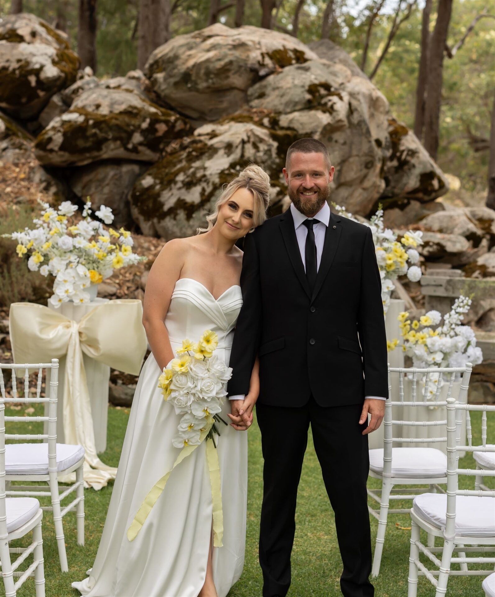 Image of a married couple in their wedding attire with yellow bouquet of flowers