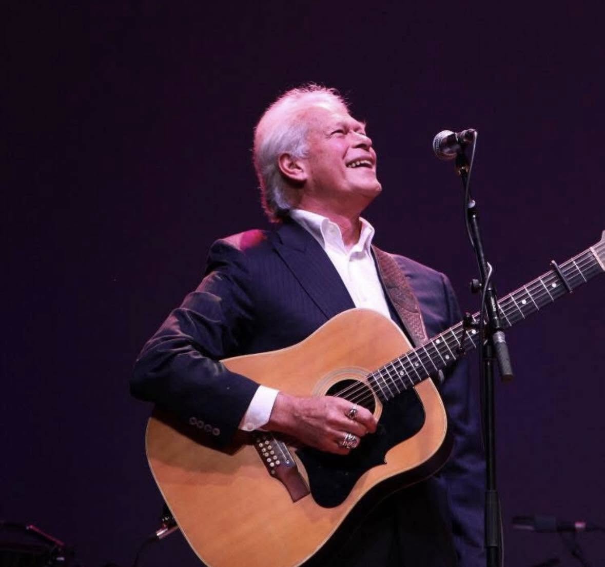 Image of The Seekers Keith Potger singing with his guitar on stage