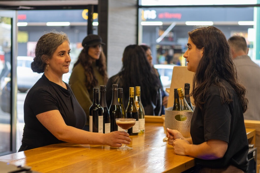 Two women speaking at a bar