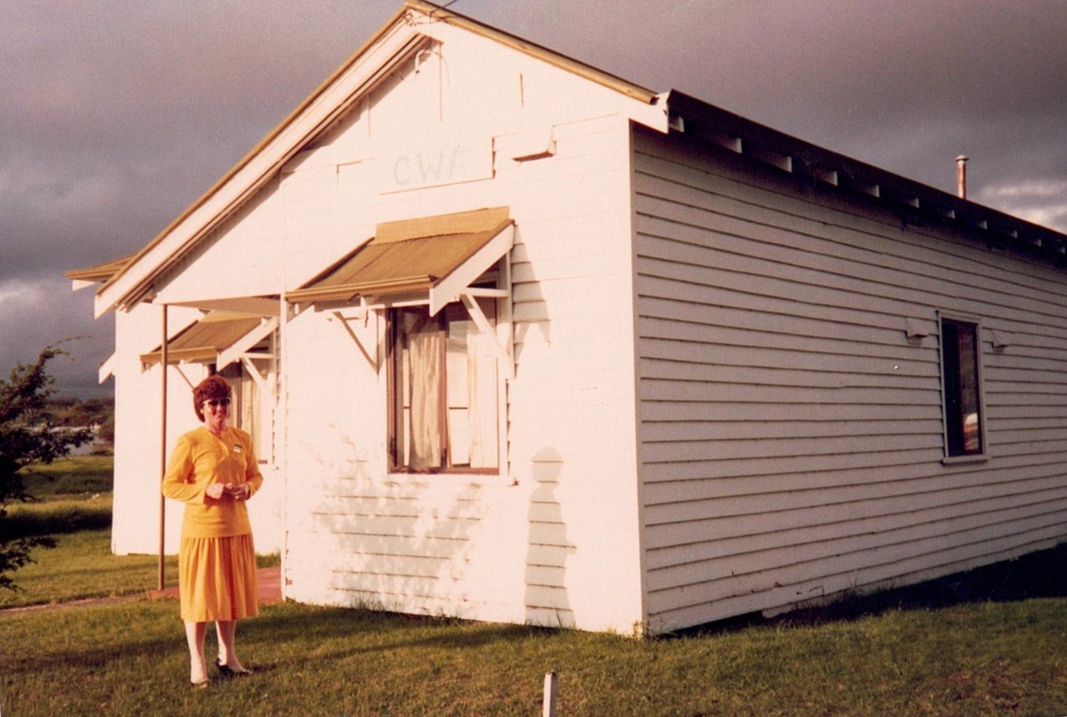 Women standing in front of weatherboard building in an orange dress